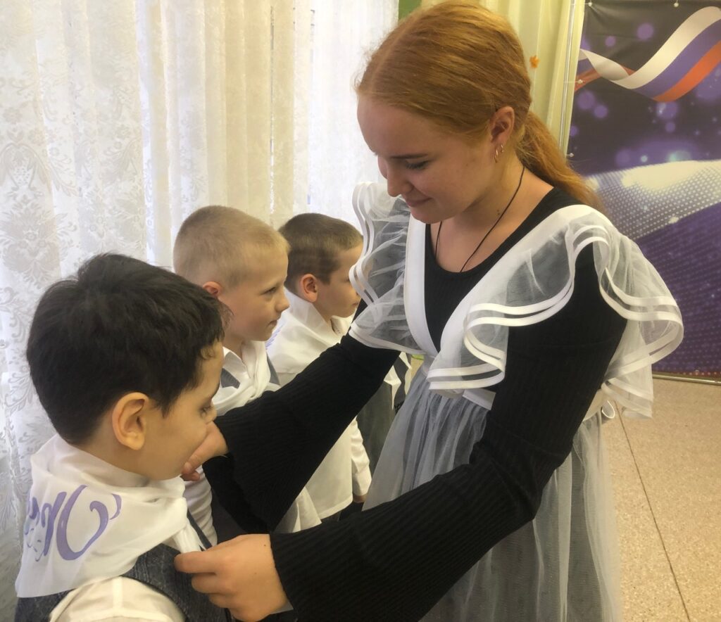 Девочка завязывает галстук